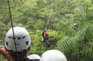 Guest riding a zip-line through the rainforest canopy on the Nativo Adventures circuit