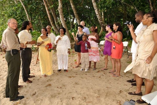 Wedding guests raising a toast on the sand after the ceremony