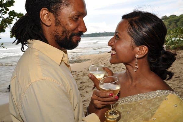 Newlyweds toasting with sparkling wine at the water's edge on Punta Uva beach